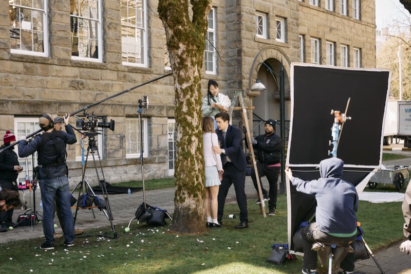 Crew setting up lighting and reflectors for an outdoor shot.