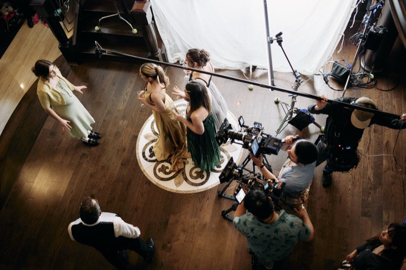 Boom operator holding a microphone above a scene in progress.